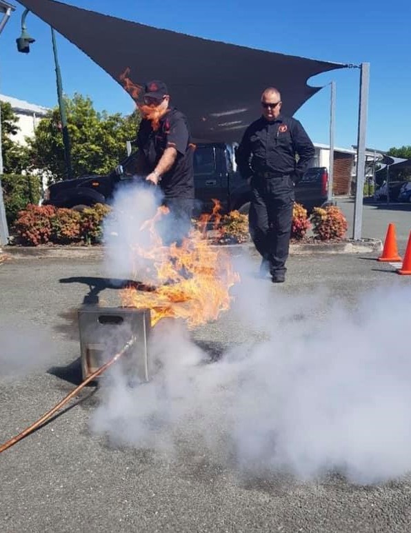 Fire extinguisher being used by two men to put out a training fire